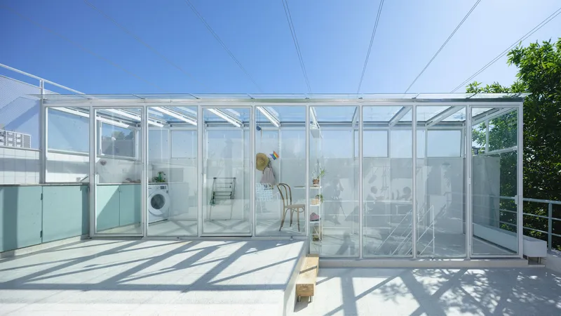 Rooftop terrace enclosed by a white steel and glass frame structure under clear blue sky