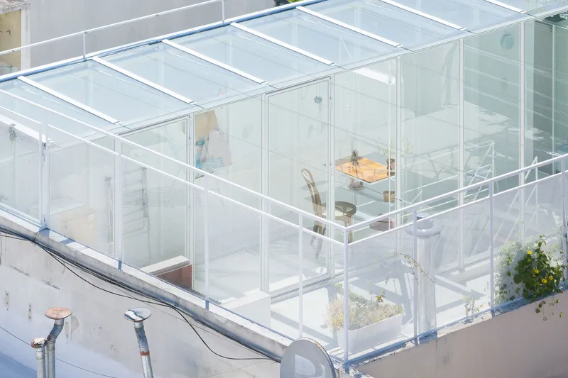 Overhead view of transparent glass box structure on rooftop with interior furnishings visible through glazing