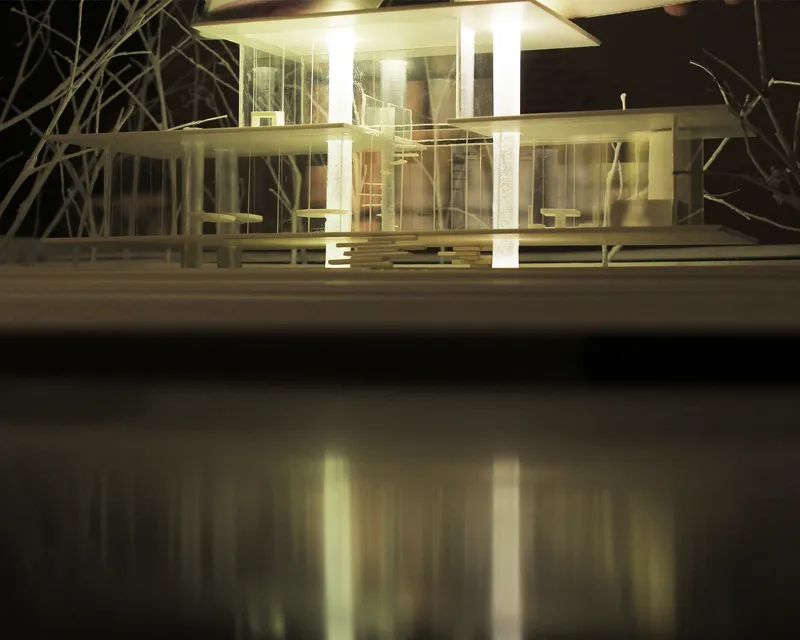 Illuminated physical model highlights layered glass volumes, horizontal planes, and slender structural elements.
