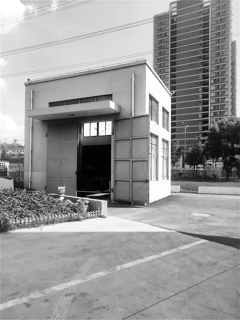 Street view of white stucco facade with cantilevered volume and residential towers behind