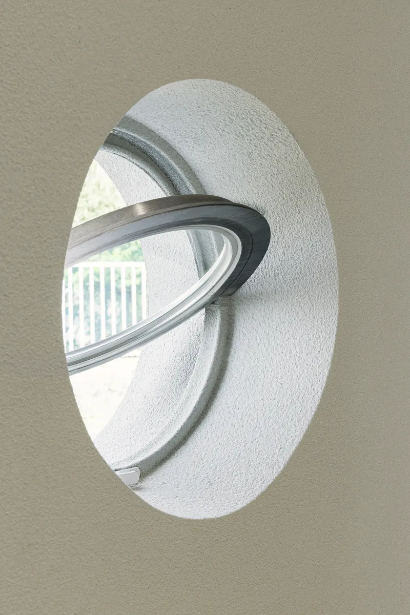 Circular window with stainless steel reveal set into textured white wall