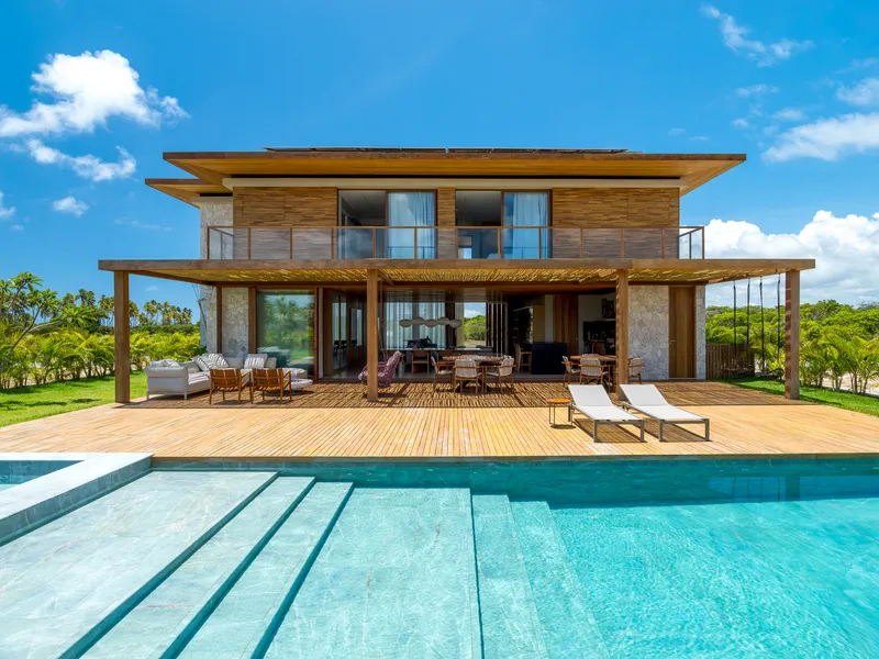 Rear facade with timber cladding and expansive decking overlooking the swimming pool on a sunny day