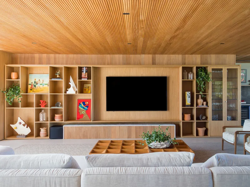 Living room media wall with gridded timber shelving and continuous ribbed ceiling in daylight