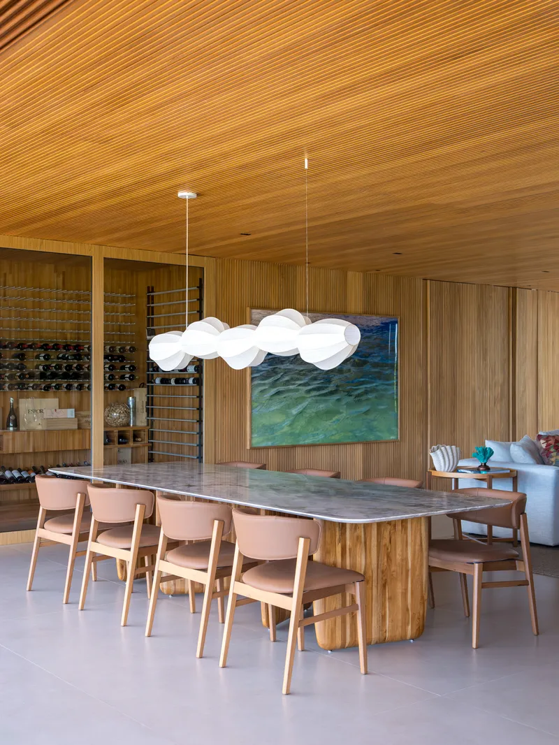 Dining room with slatted timber ceiling and cloud-shaped pendant light above a long marble-topped table