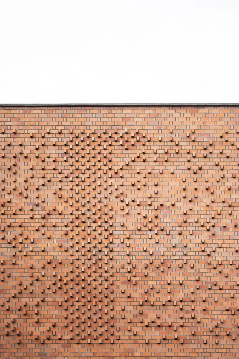 Patterned brick facade with projecting and recessed bricks forming a diamond motif