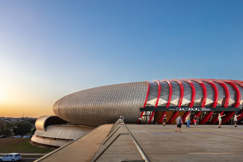 Long concrete pedestrian ramp leading to the entrance with red arched ribs at sunset
