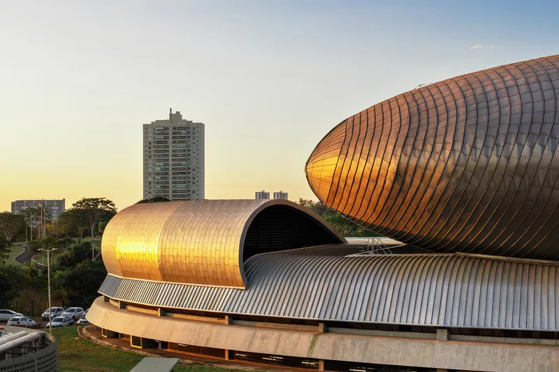 Tubular ribbed metal roof forms stacked and interlocking above a concrete base at golden hour