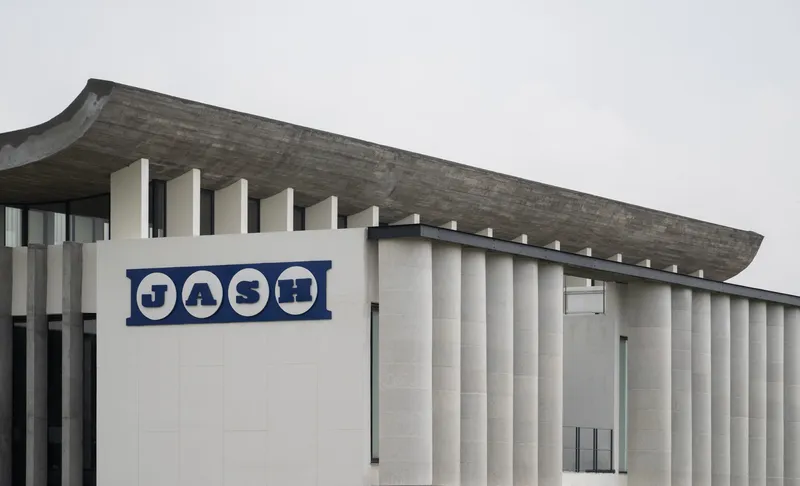 Close-up of the signage panel against the vertical ribbed concrete facade under grey sky