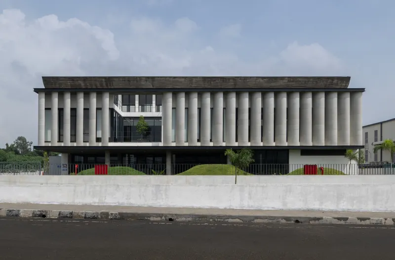 Street view of the precast concrete columnar facade rising above a concrete retaining wall
