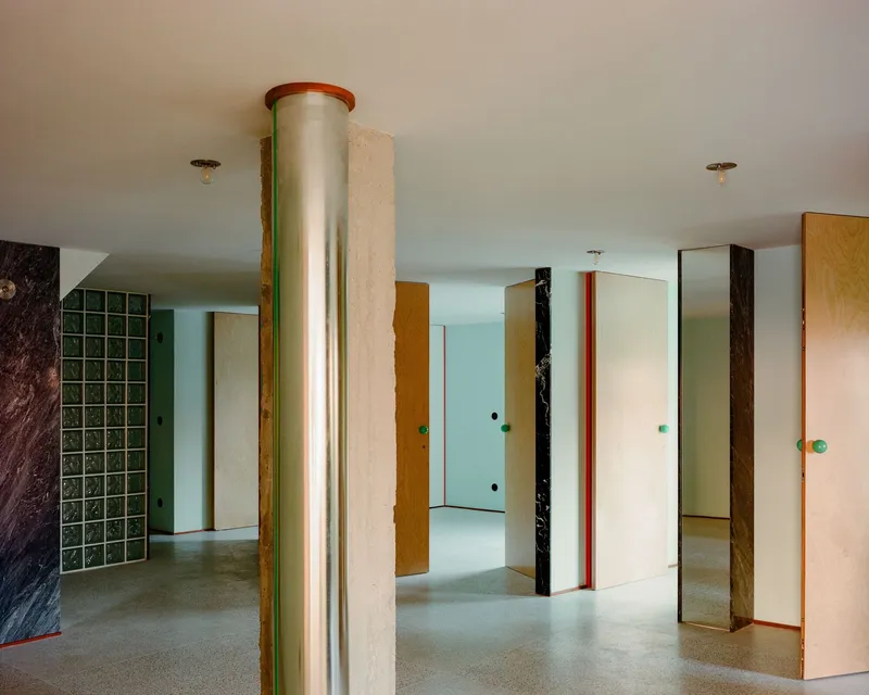 Interior space with cylindrical column wrapped in red trim and freestanding partition panels in varied finishes