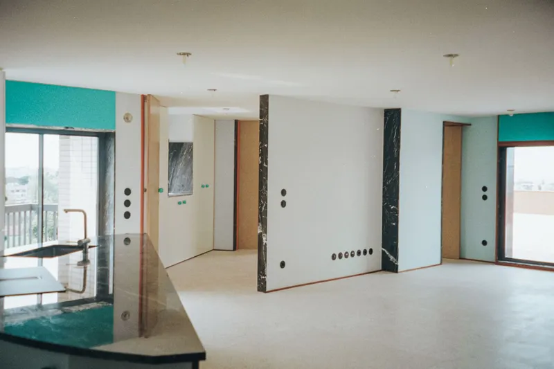 Open-plan interior with marble-clad partitions, pale wood cabinetry, and windows framing the cityscape