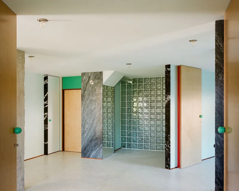 Corner view showing marble wall panels flanking a glass block partition with turquoise backing