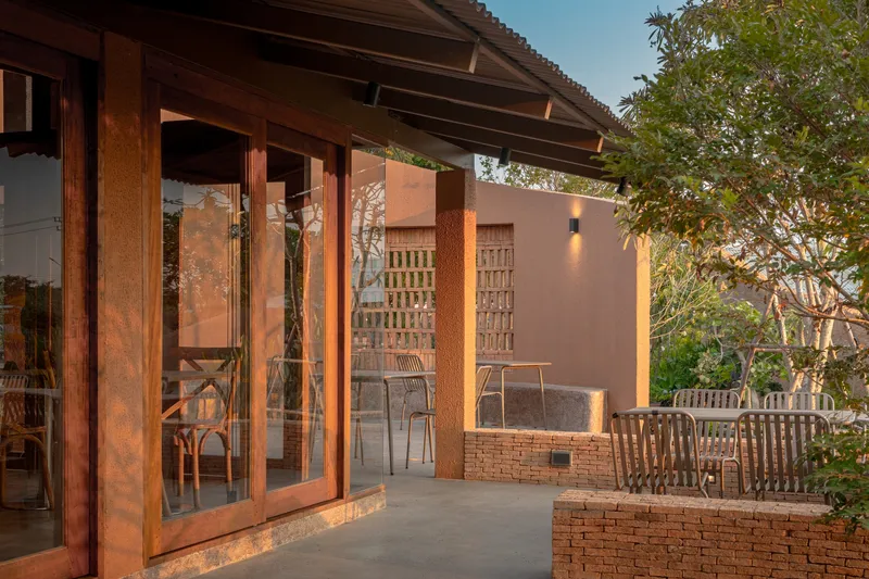 Timber folding doors opening to terrace with brick planter walls and lattice screen at twilight