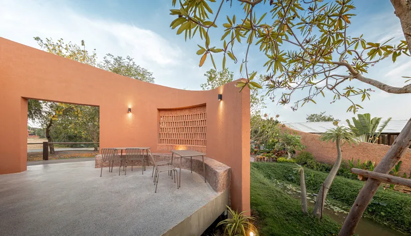 Outdoor terrace with latticed brick screen and framed view to the landscape under a plumeria tree
