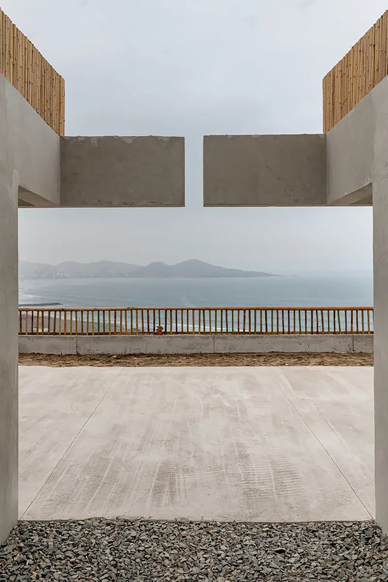 Concrete portal framing a timber railing and distant coastal mountains across the water