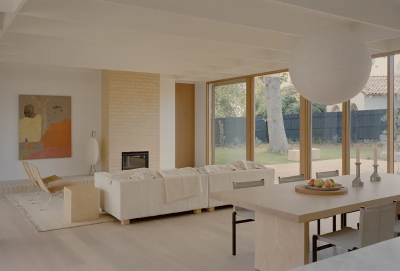 Living room with cream brick fireplace and full-height windows overlooking lawn and eucalyptus tree