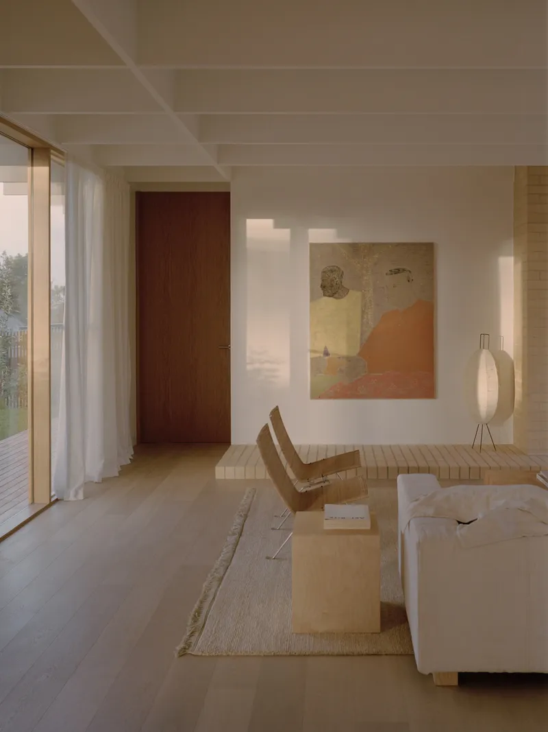 Interior corridor with dark timber door and lounge seating in late afternoon sunlight