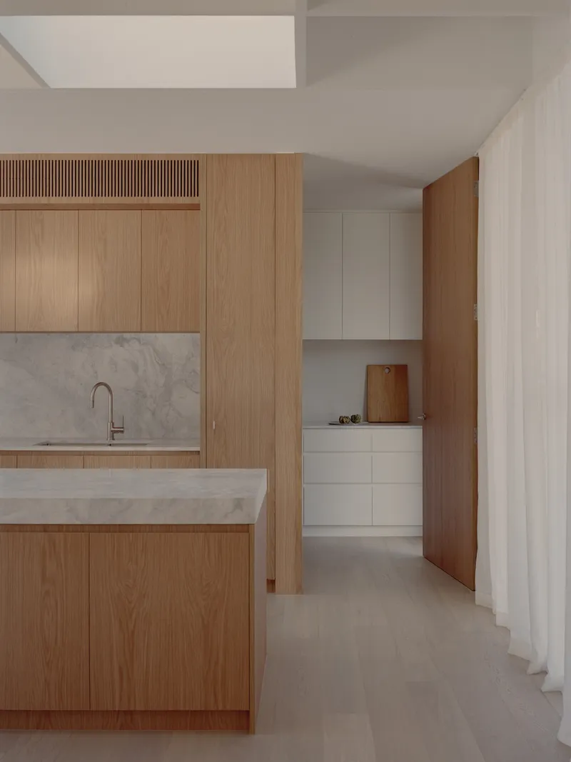 Kitchen with oak veneer cabinetry and marble countertop island beneath skylights