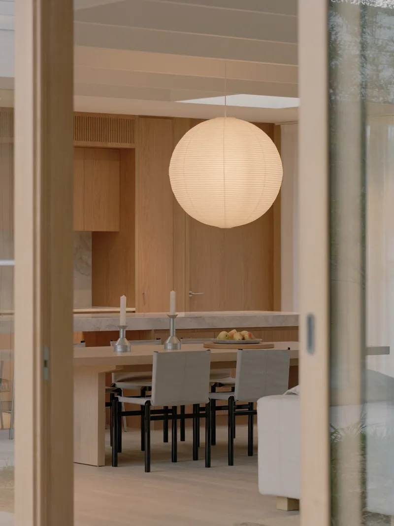 View through glazed doorway to dining table beneath spherical pendant light