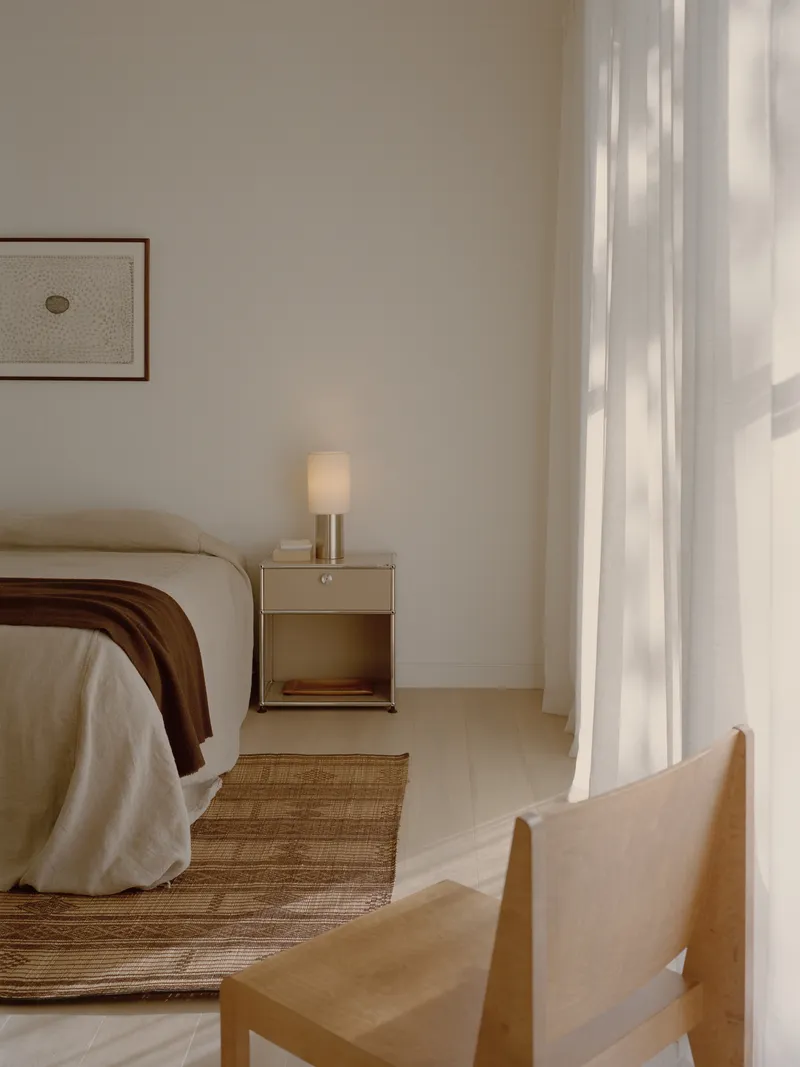 Bedroom corner with bedside table and linen curtains filtering afternoon light