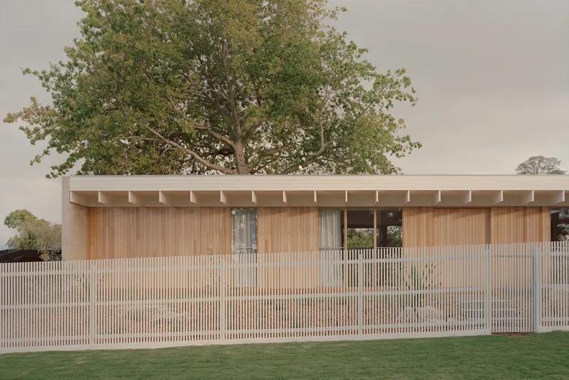 Horizontal timber slat fence screening the timber-clad facade beneath an overcast sky