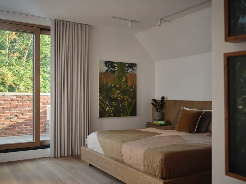 Bedroom with timber bed frame and wood-framed sliding door opening to a brick terrace
