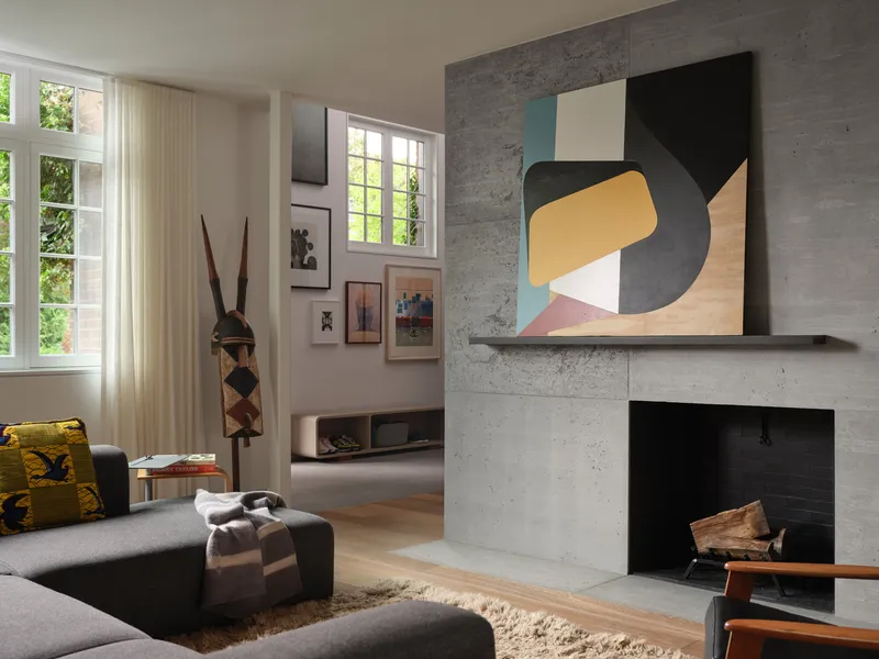 Concrete fireplace surround with black firebox opening and white-painted window alcove in daylight