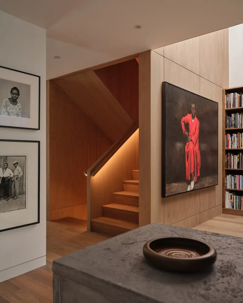Timber-clad stairwell with integrated lighting beneath the treads and adjacent bookshelf