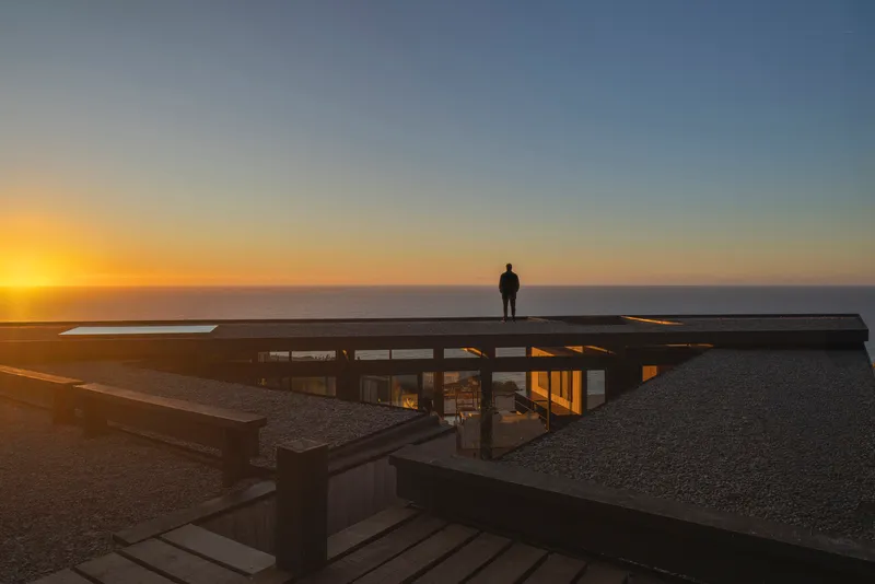Flat roof with skylight and figure silhouetted against the ocean horizon at sunset