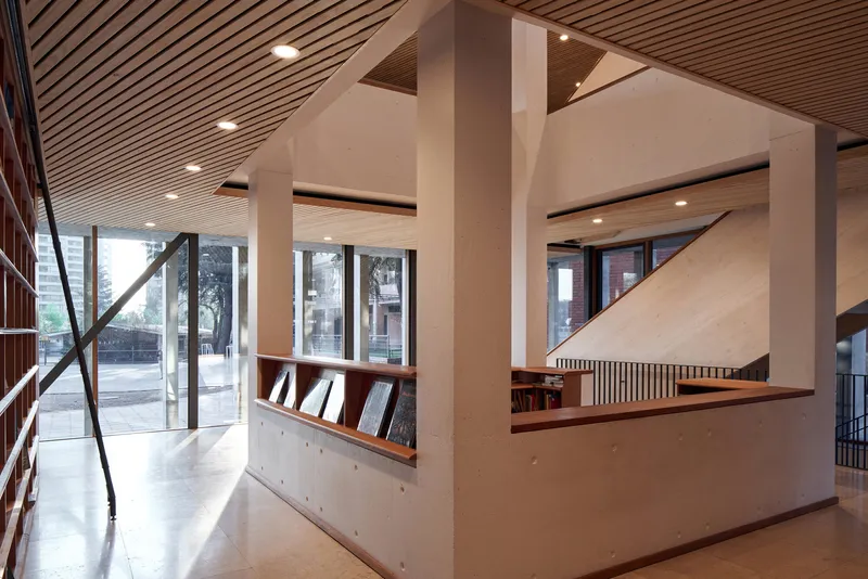Library interior showing plywood balustrade, white concrete columns and diagonal steel bracing at the glazed facade