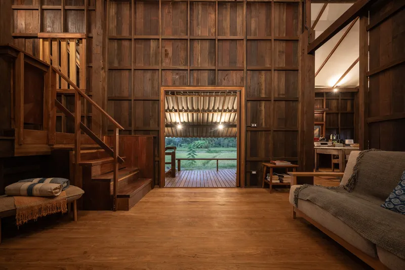 Timber-paneled interior with staircase and framed doorway opening to deck at dusk