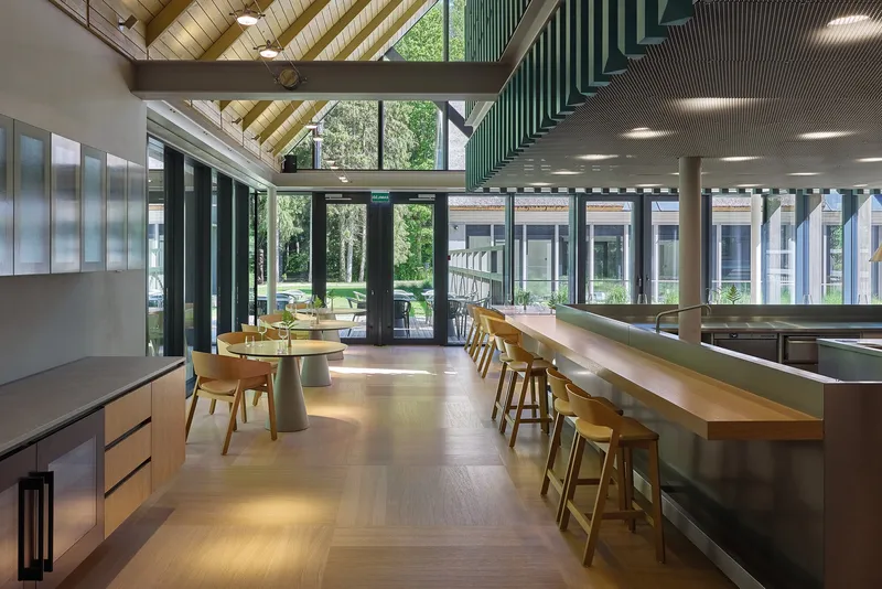 View through the dining space toward glazed doors opening onto a lawn with trees beyond