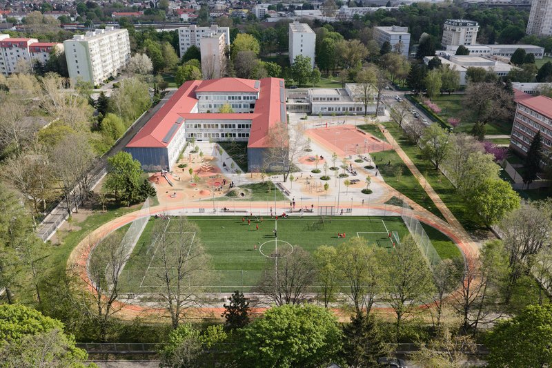 Aerial view of the school complex with terracotta roofs and adjacent sports pitch