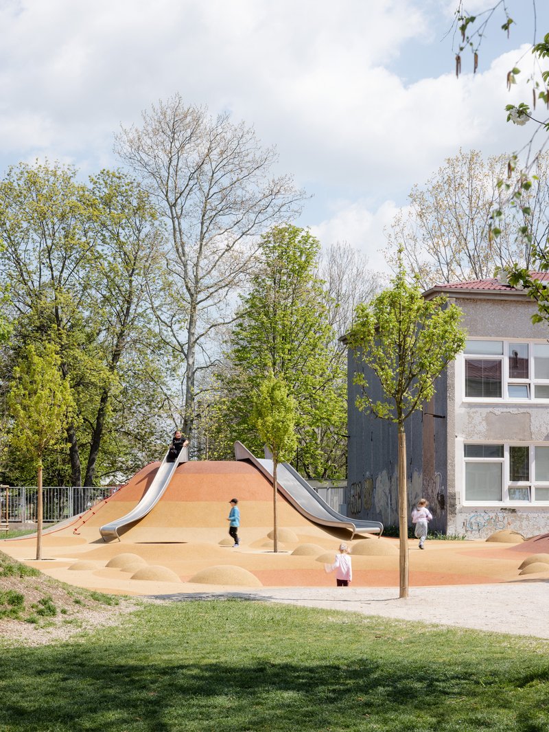 Playground slide structure with children at play among spring trees