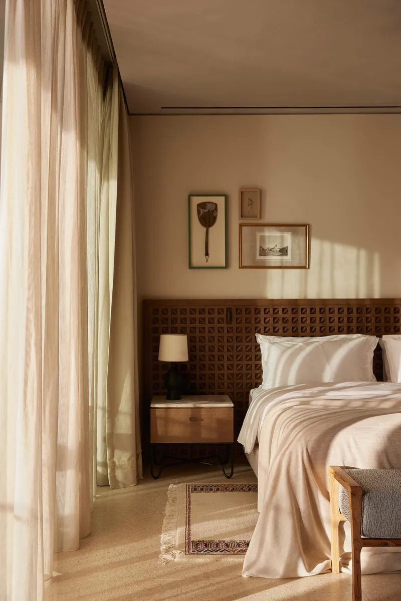 Bedroom interior with carved wood headboard and sheer curtains filtering warm afternoon light