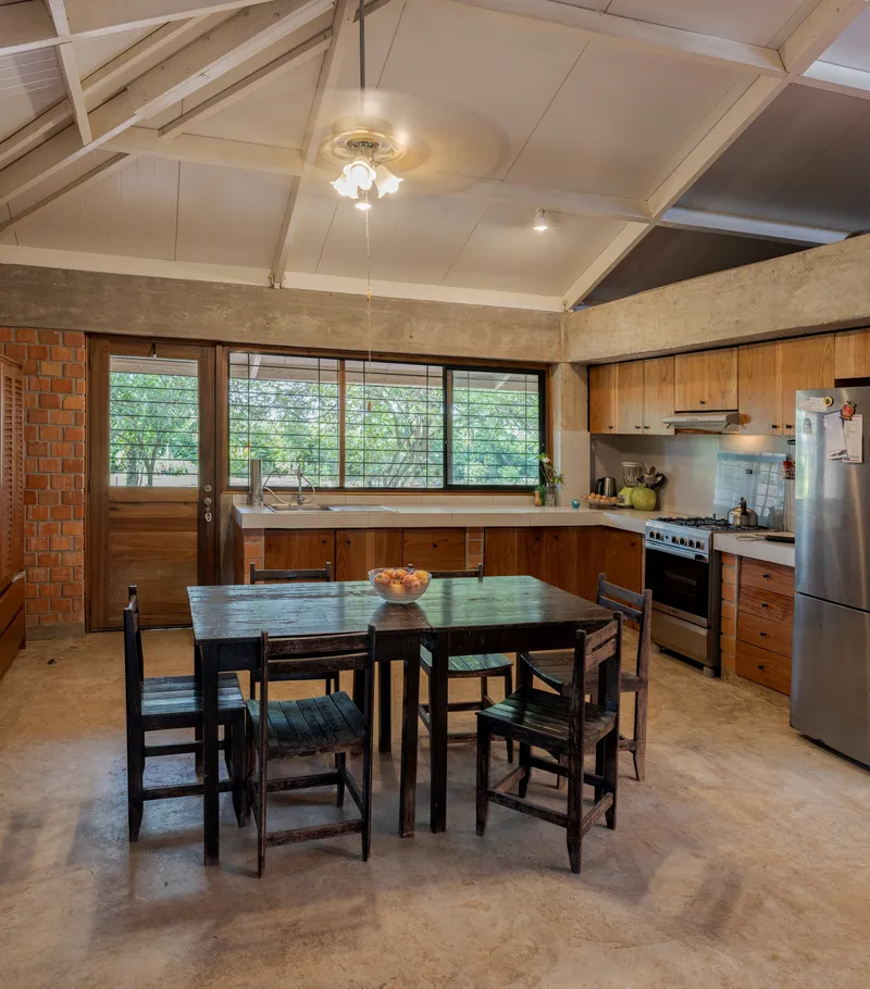 Kitchen and dining area with timber cabinetry, horizontal louvre windows, and vaulted timber ceiling