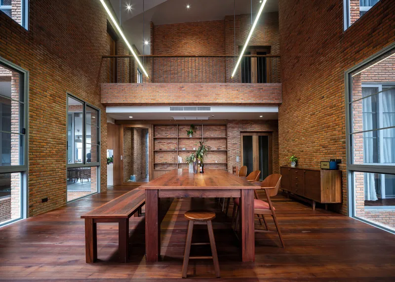Double-height dining space with exposed brick walls and a timber mezzanine bridge above