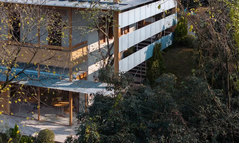 Elevated view of tiered terraces with corrugated metal roofs nestled into a sloped garden with bare trees