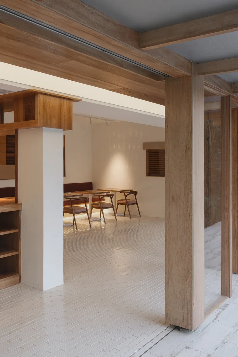 Interior view through timber portal frame into dining area with exposed ceiling beams
