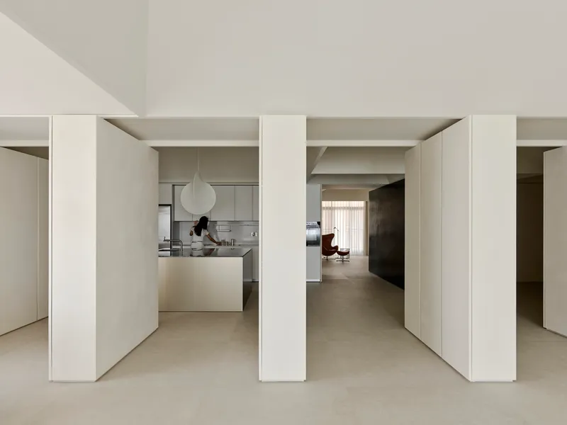 Repeating white columns dividing interior spaces with kitchen and seating areas glimpsed through openings