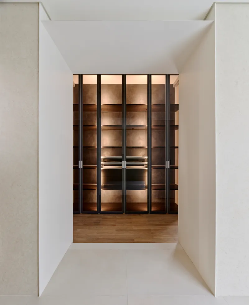 View through a white portal to illuminated glass and metal shelving units on wooden flooring