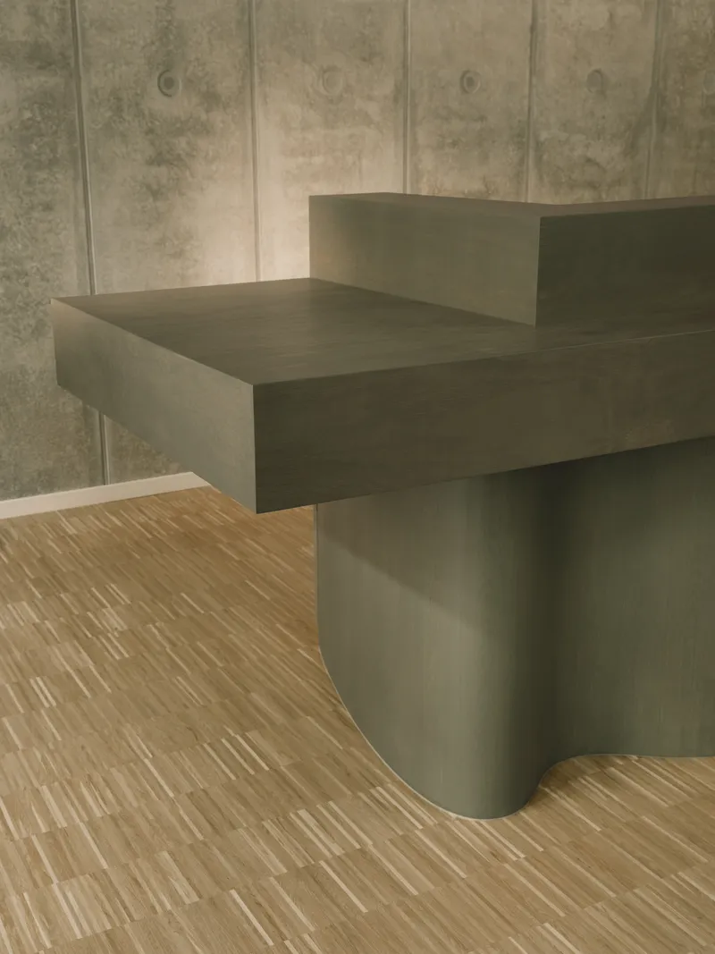 Cantilevered timber reception desk with curved base meeting striped oak flooring against board-formed concrete wall