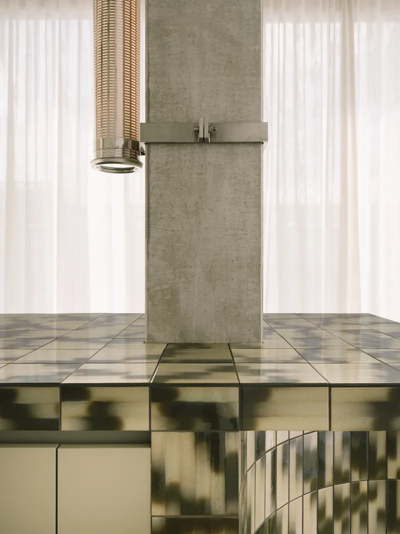 Concrete column with rattan pendant fixture above a reflective chequered floor adjacent to sheer curtains