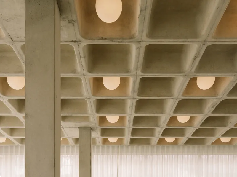 Concrete column supporting a waffle slab ceiling with integrated globe lighting in rectilinear coffers