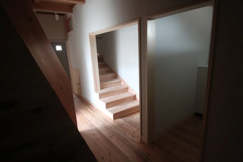 Timber staircase framed by white walls and timber doorways under diffused natural light