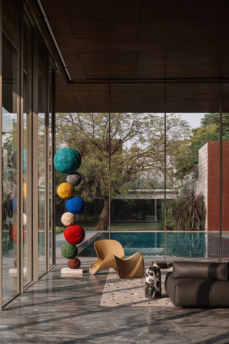 Interior corner with floor-to-ceiling glass looking out to the pool and a hanging sculpture of colored spheres