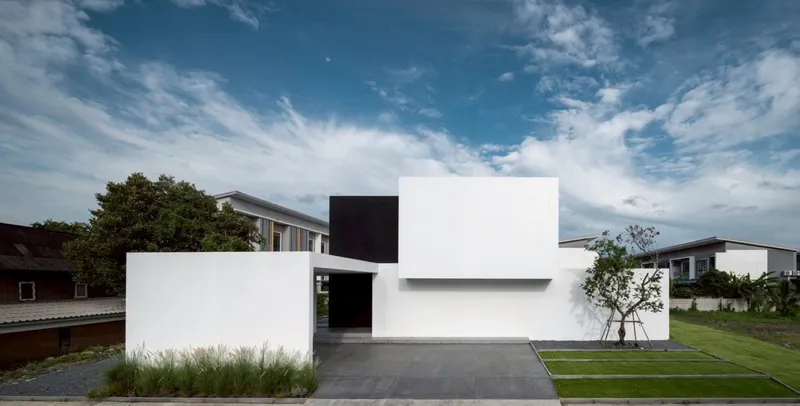 Street view of white geometric volumes with a black cantilevered box and covered entry