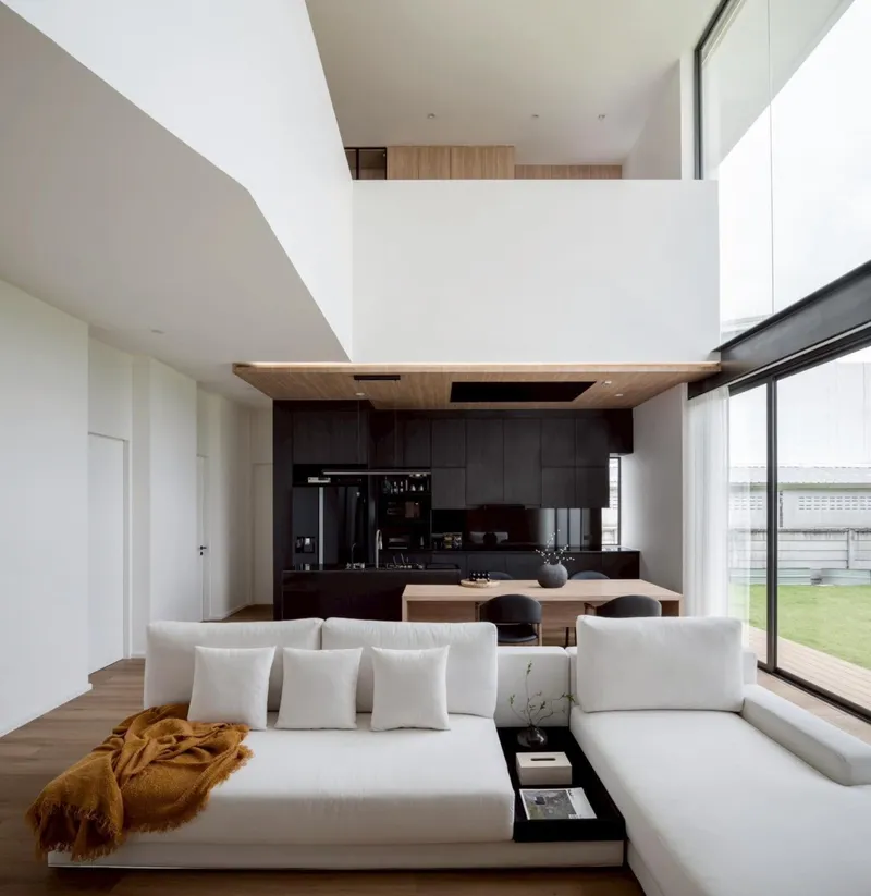 Double-height living space with dark timber kitchen cabinetry and a floating volume above