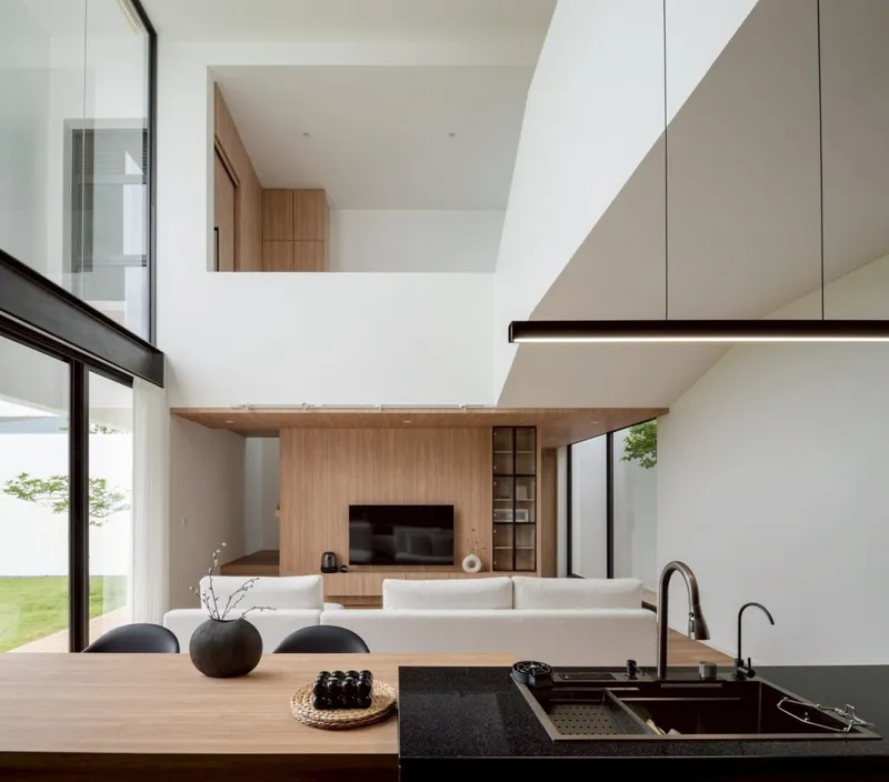 Double-height living space with timber media wall and kitchen island overlooking the lawn