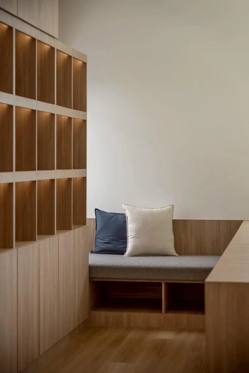 Built-in window seat with cushions beneath timber shelving and horizontal slat detailing
